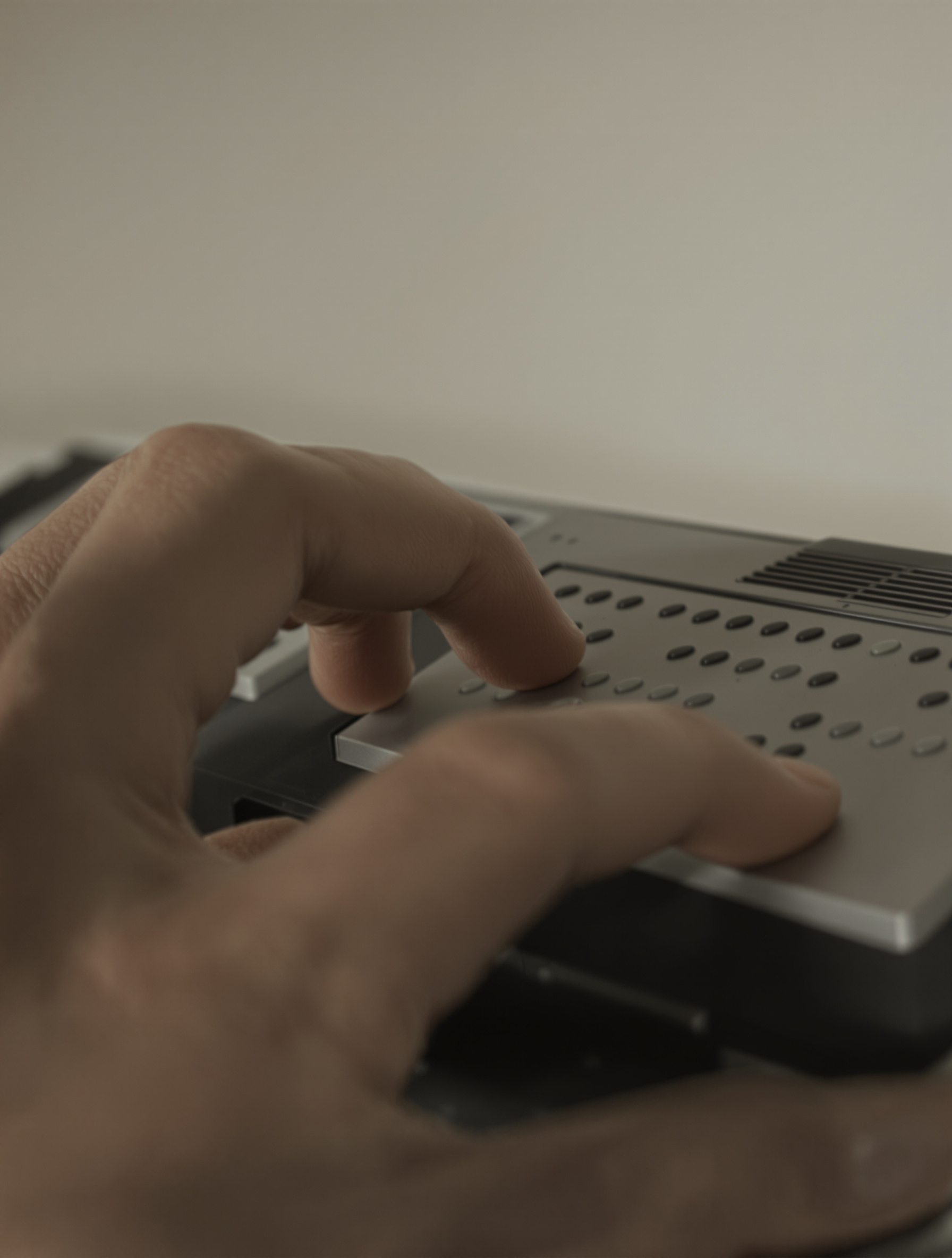 Une main tapant sur un clavier braille, ambiance déterminée et sobre.